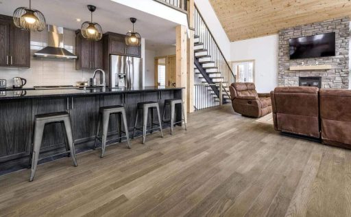 Wide hardwood floor planks in an open kitchen and living area showing their effect on space and design