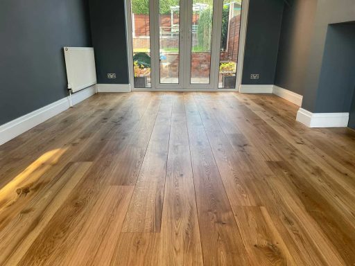 Hardwood floor after sanding and cleanup showing a clean dust-controlled refinishing result in a finished room