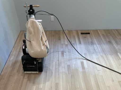 Hardwood floor sanding machine on thick floorboards showing the kind of surface material that affects refinishing potential and long-term durability