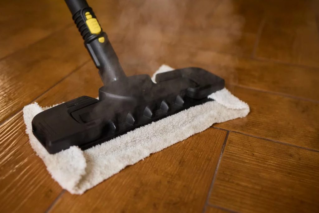 Steam mop on hardwood floor showing a cleaning method that can introduce heat and moisture into wood flooring