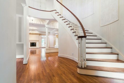 Dark stained hardwood floor with curved staircase showing a rich finished surface and a more formal whole-home look