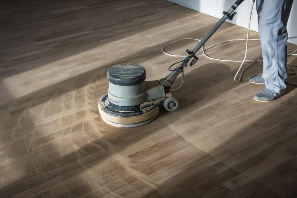 Hardwood floor buffing before refinishing showing machine prep work that affects labour time and total project cost