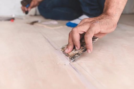 Applying wood filler to hardwood floor seams before sanding blending and refinishing