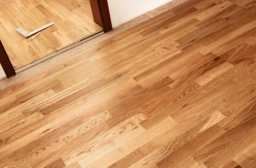 Solid hardwood floor across doorway showing continuous strip flooring and natural wood variation through adjacent spaces