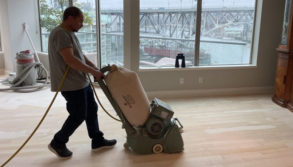 Professional sanding hardwood floor with drum sander during surface preparation before final finishing coats