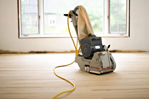 Hardwood floor sanding machine on bare wood floor during full refinishing and restoration work