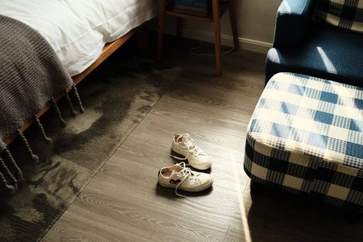 Bedroom hardwood floor with rug and shoes showing everyday foot traffic and common contact points that can affect floor wear and noise
