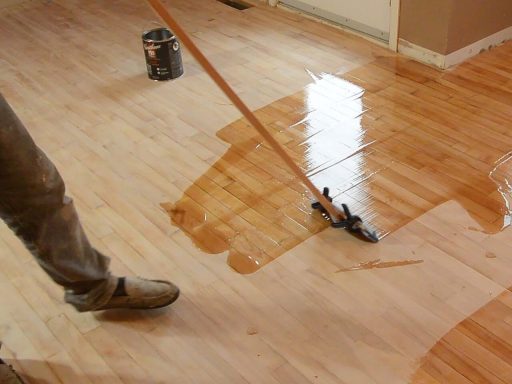 Applying finish during hardwood floor refinishing to seal the surface and build a fresh protective layer