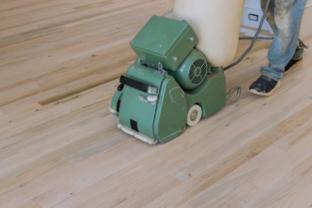 Hardwood floor sanding machine removing the old finish during full scratch repair and refinishing