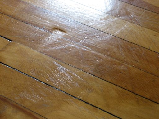 Scratches on wood floor finish close up showing surface wear light gouges and visible finish damage