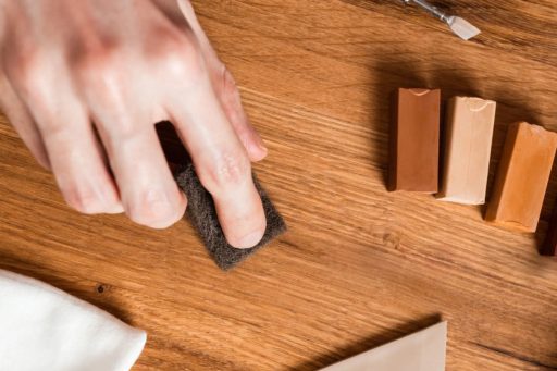 Touch up repair on hardwood floor using color-matched materials to blend small scratches and surface marks