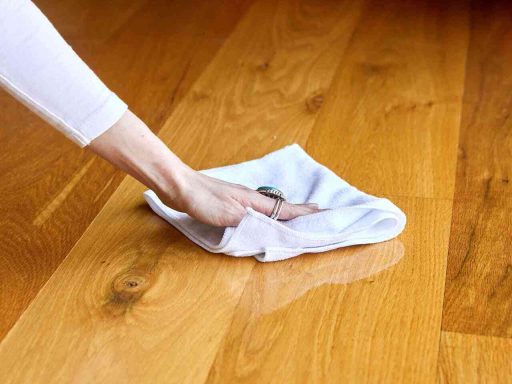 Wiping spill from hardwood floor right away to prevent moisture from soaking into the finish and wood