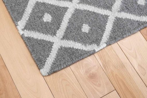 Small gap between hardwood floor boards near rug edge showing seasonal wood movement