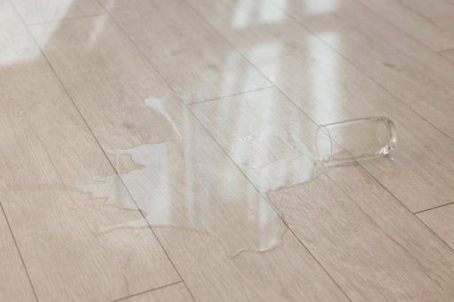 Water spill on a hardwood floor from an overturned glass