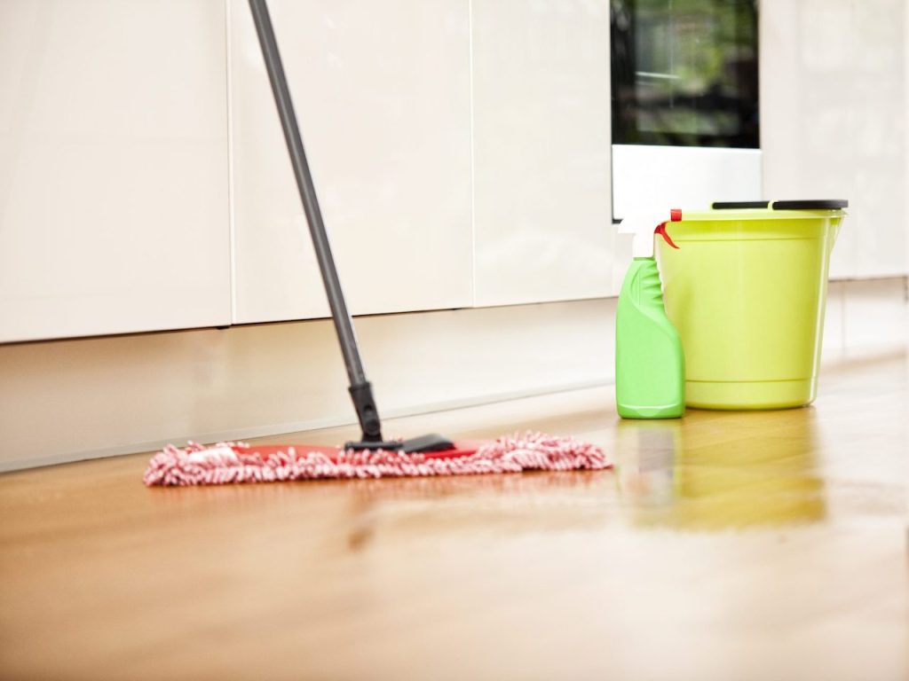 Cleaning hardwood floors with a damp microfiber mop during routine floor care