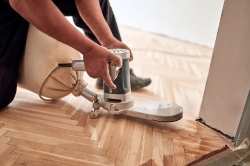 Edge sanding hardwood floor with edger machine near wall perimeter