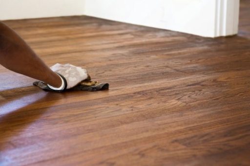 Applying finish to hardwood floor during refinishing to restore appearance and extend the life of the surface
