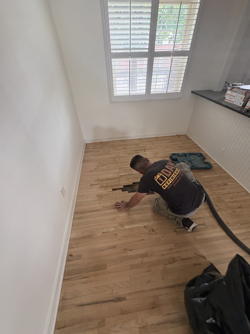 Hardwood floor repair process with damaged boards removed for replacement in a small room