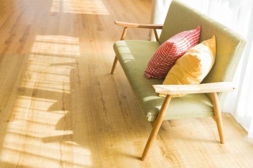 Smooth natural-tone hardwood floor after refinishing in a bright living space with an armchair