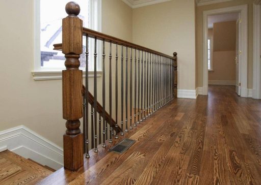 Upstairs hallway with freshly refinished hardwood flooring and wooden stair railing