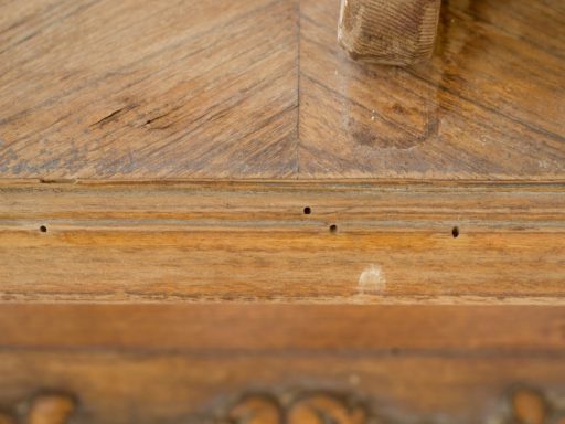 Small holes in hardwood floor near board edge before filler repair sanding and refinishing