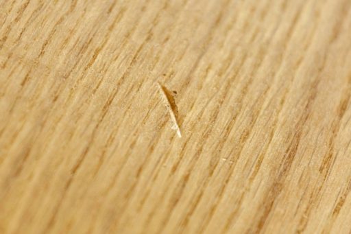 Small scratch on hardwood floor close up showing light surface damage