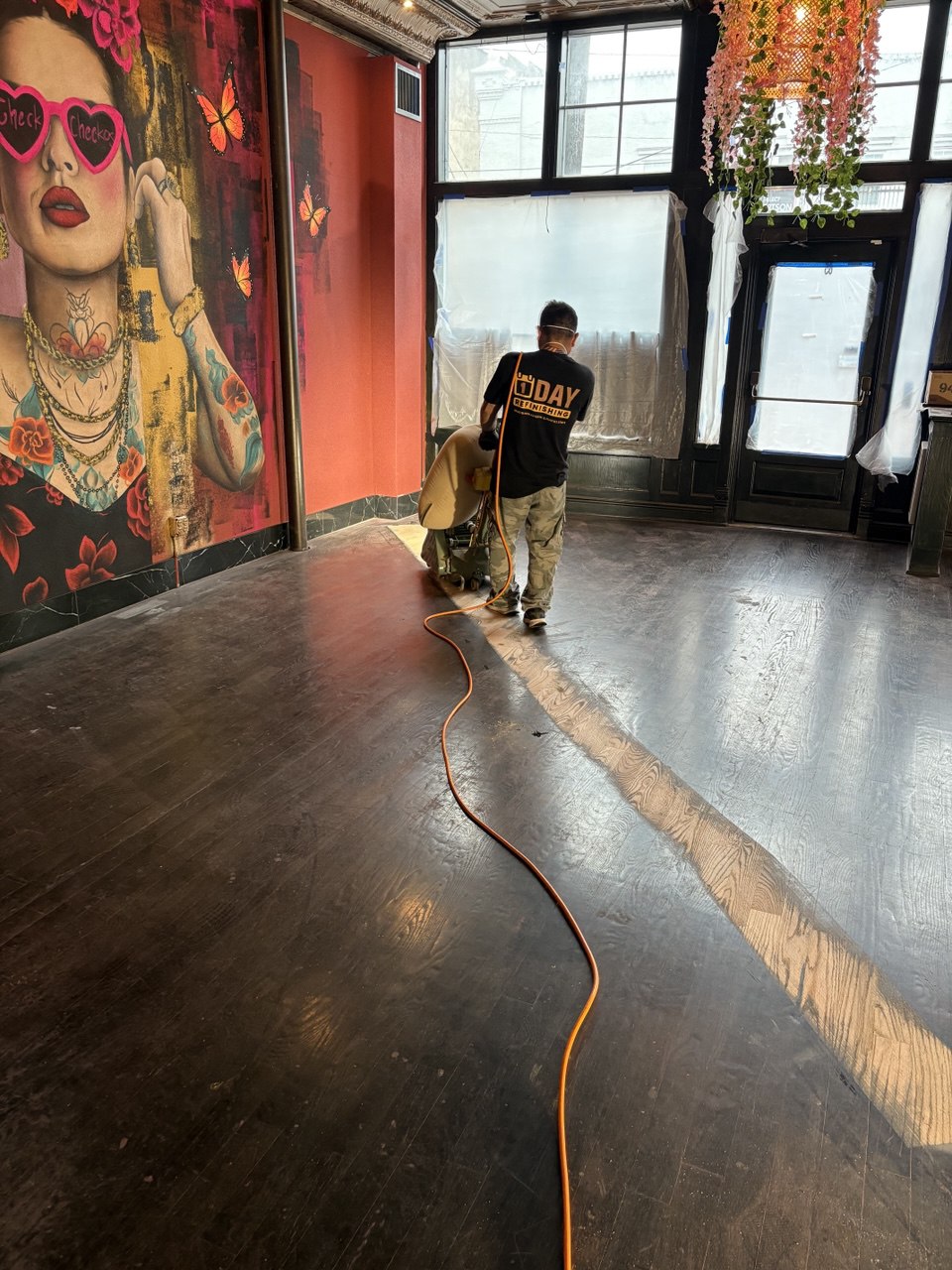 Hardwood floor sanding and refinishing in commercial space using professional floor sander during wood floor restoration process
