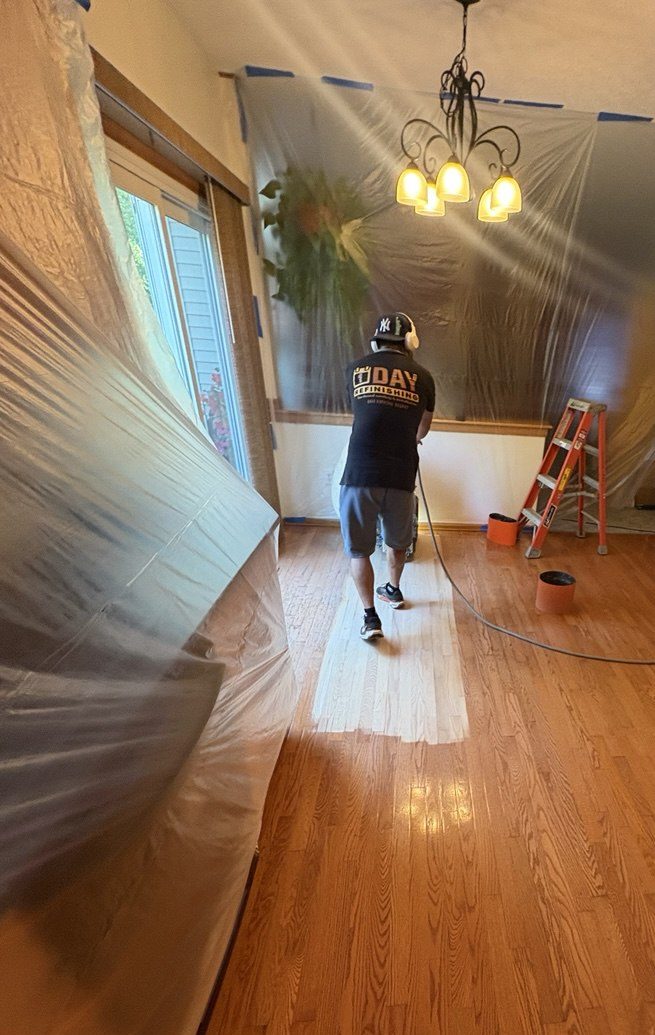 Hardwood floor refinishing preparation with dust containment plastic and contractor sanding floor